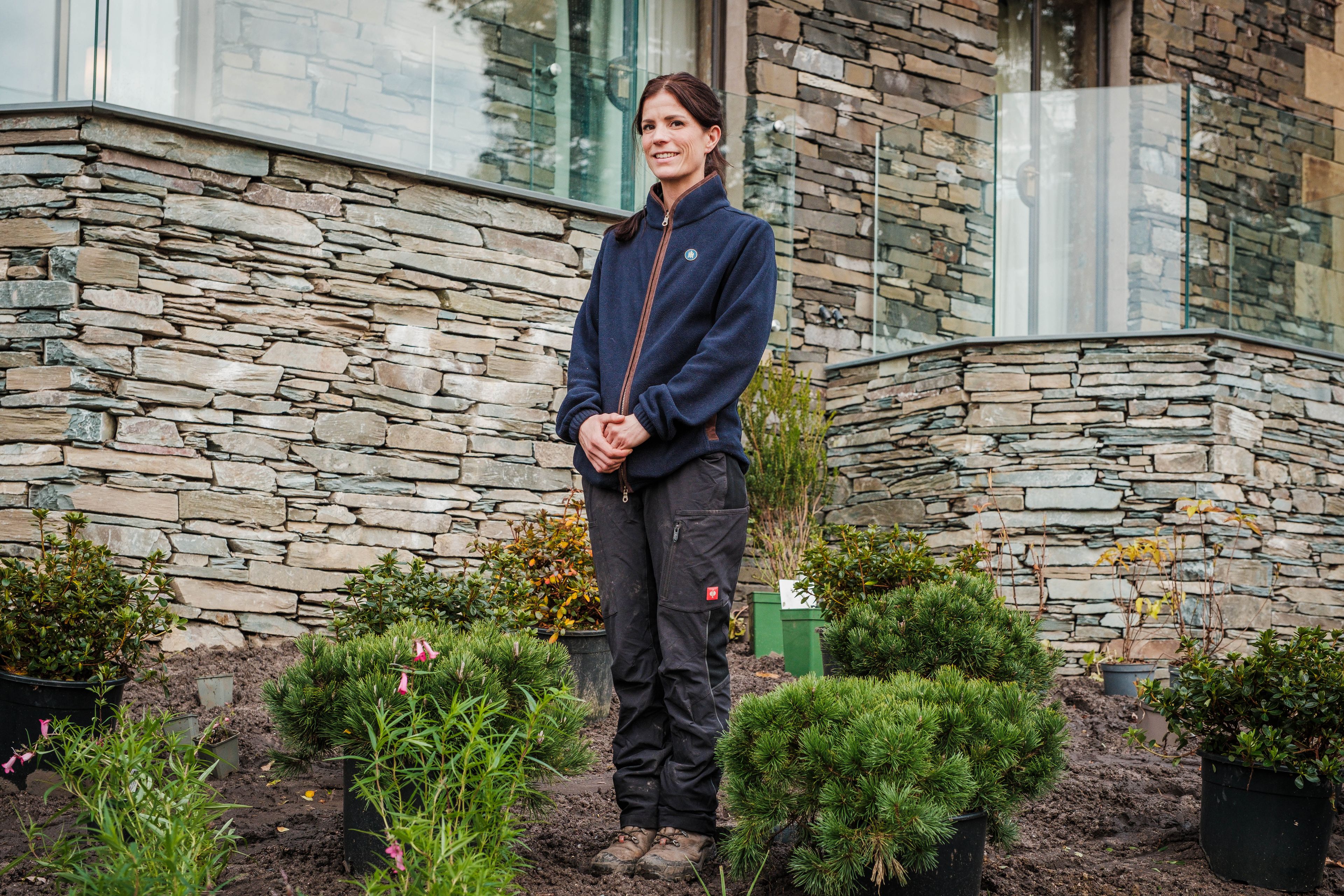 A woman among the plants, standing and smiling