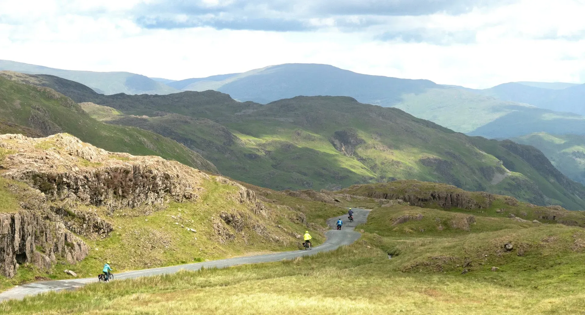 bikers biking down a winding path in the mountains