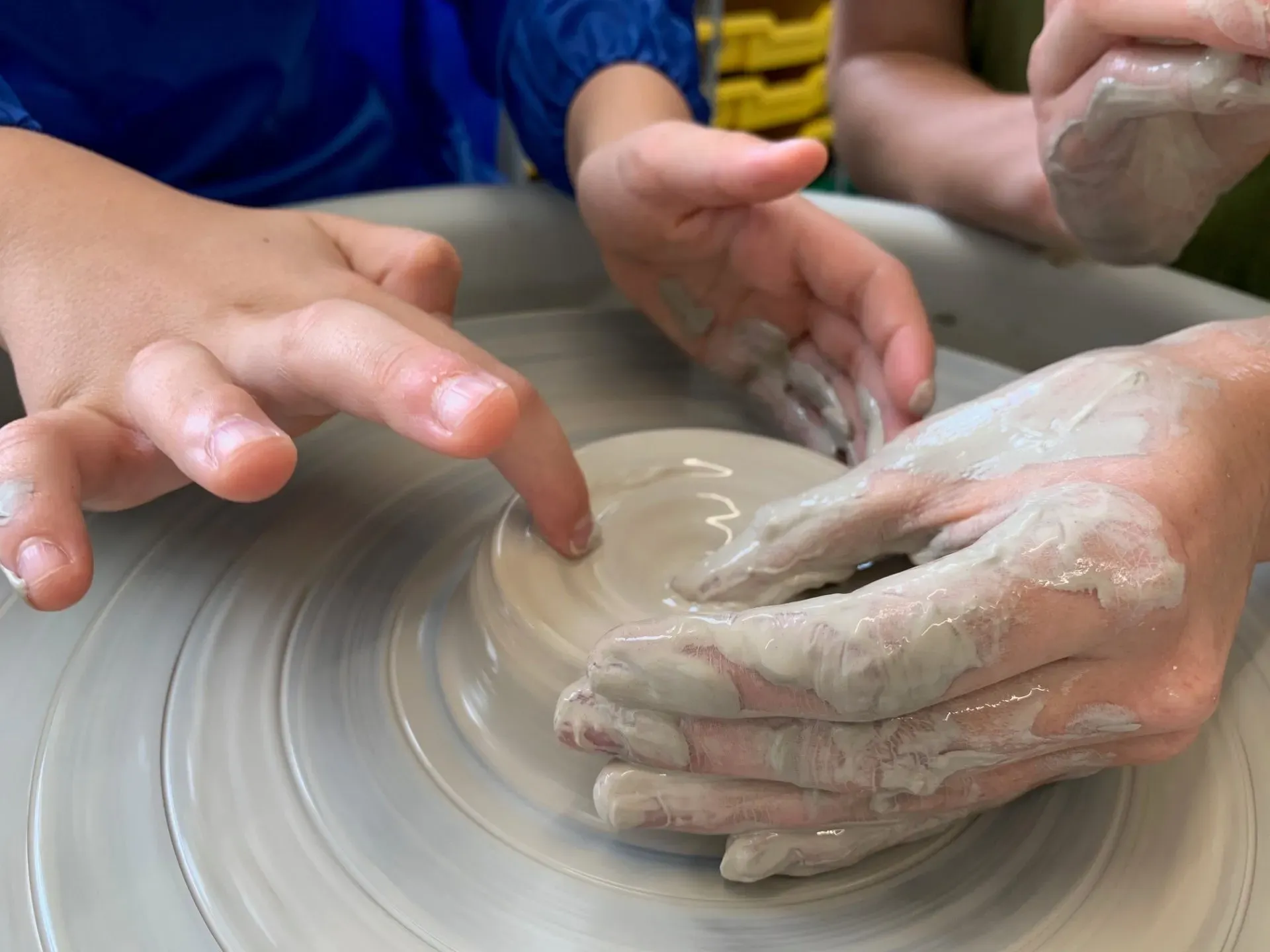 child being taught how to make ceramics